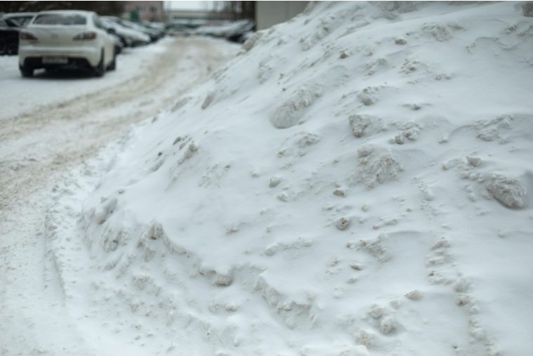 Large pile of snow in a Brooklyn lot explaining snow removal contract vs per-visit cost options. Large pile of snow in a Brooklyn lot explaining snow removal contract vs per-visit cost options.